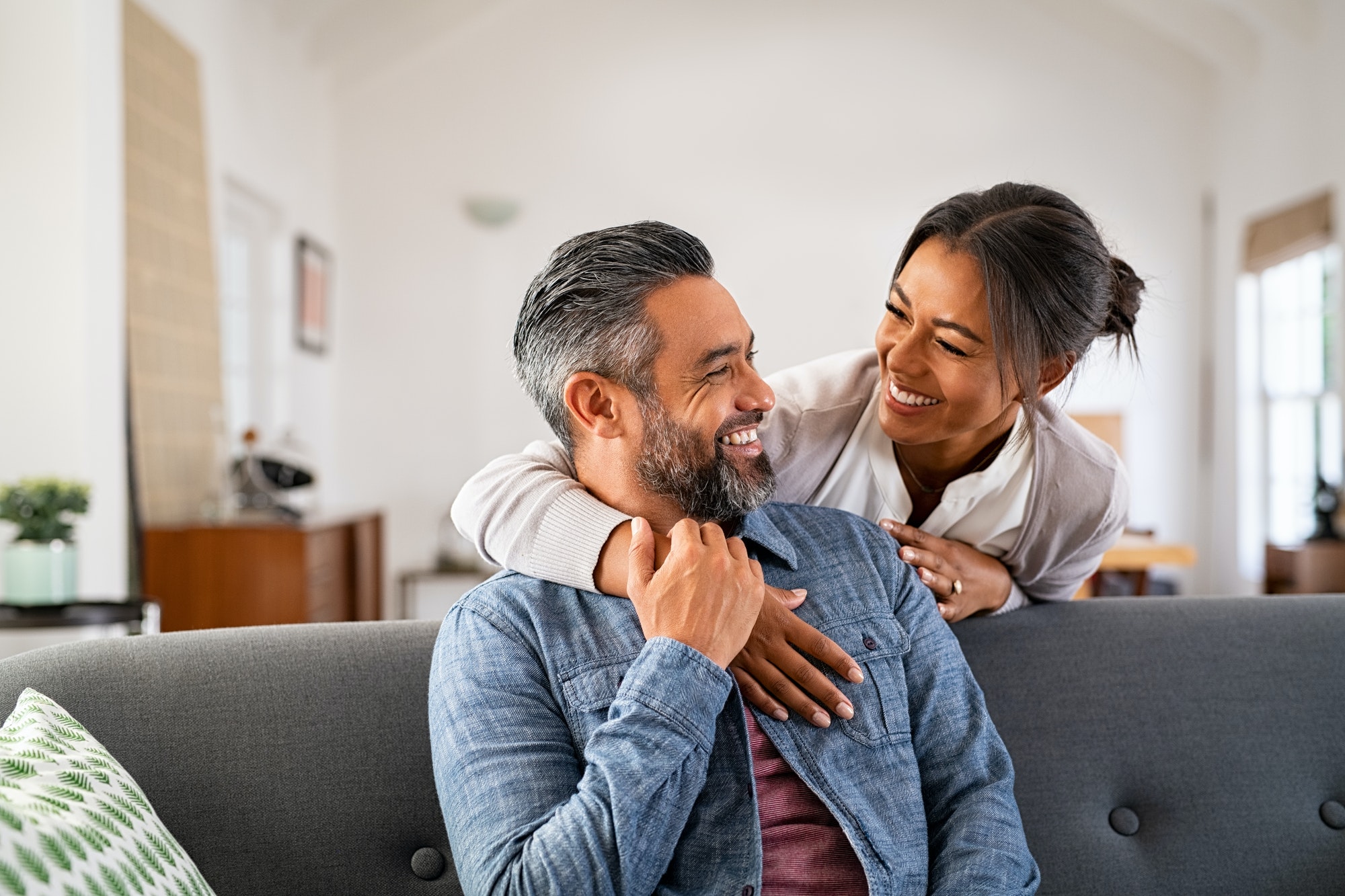 Mature multiethnic couple laughing and embracing at home