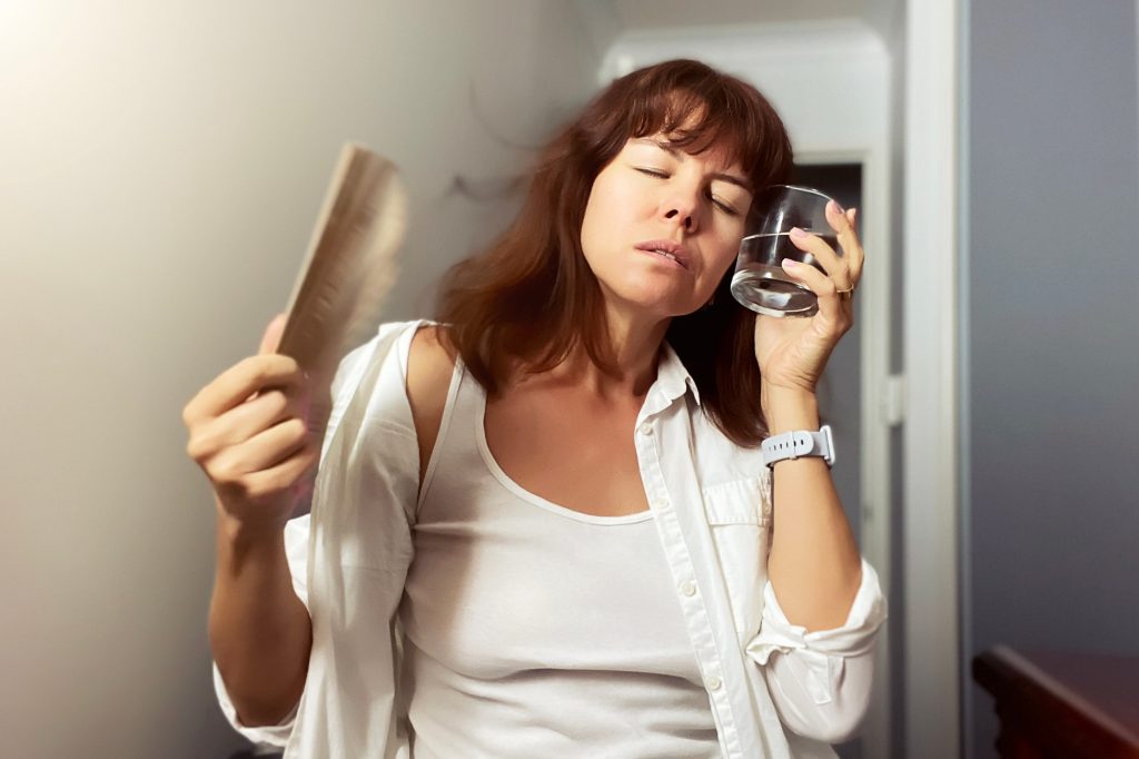 A woman cooling down with a fan and glass of water